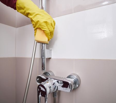 Housecleaner in rubber glove washing plumbing fixture