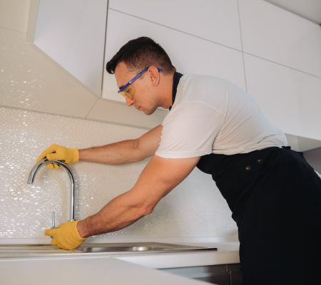 Maintenance man installing plumbing equipment in the kitchen