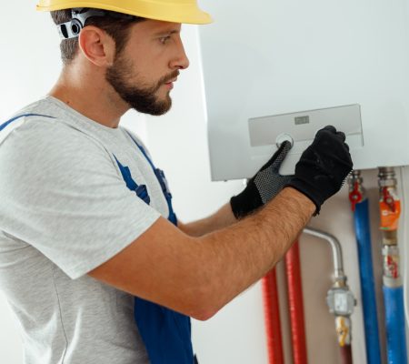 Serious technician setting the new gas boiler for hot water and heating